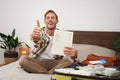 Cheerful young man, tourist with check list, showing his notes in notebook, thumbs up, packing suitcase, going on Royalty Free Stock Photo