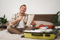 Cheerful young man, tourist with check list, showing his notes in notebook, thumbs up, packing suitcase, going on Royalty Free Stock Photo