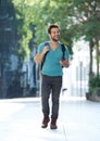 Cheerful young man walking with mobile phone and bag Royalty Free Stock Photo