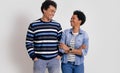 Cheerful young man and woman smiling and looking at each other while standing over white background Royalty Free Stock Photo