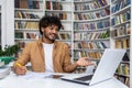 Cheerful young man working on laptop in library Royalty Free Stock Photo