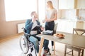 Cheerful young man with inclusiveness sit at table and talk on phone. He look at woman and smile. Holding opened folder Royalty Free Stock Photo