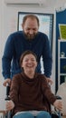 Cheerful young man pushing wheelchair with his disabled paralysed coworker Royalty Free Stock Photo