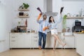 Cheerful young men and women imitate rock stars while taking care of the house. Happy young couple