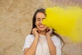 Cheerful young model having fun in a cloud of yellow dry powder, celebrating Holi colors festival at the desert Royalty Free Stock Photo