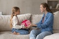 Cheerful young mother giving gift to little daughter. Royalty Free Stock Photo