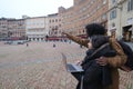 Cheerful young multiethnic couple of tourists with laptop visiting historical town of Siena, Italy