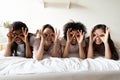 Cheerful young multiracial girls having fun on bed at sleepover