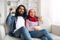 Muslim couple relaxing on couch with popcorn, having movie night at home, Royalty Free Stock Photo