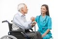 Cheerful young nurse holding senior man hand and sm