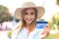 Cheerful young optimistic girl standing outdoors, holding credit card in hand