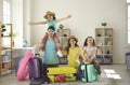 Cheerful young parents and their daughters sitting on the floor and packing suitcases for a trip. Royalty Free Stock Photo