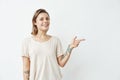 Cheerful young pretty girl smiling looking at camera pointing finger in side over white background. Royalty Free Stock Photo