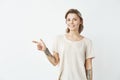 Cheerful young pretty girl smiling looking at camera pointing finger in side over white background. Royalty Free Stock Photo