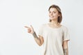 Cheerful young pretty girl smiling looking at camera pointing finger in side over white background. Royalty Free Stock Photo