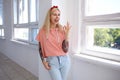 Cheerful young pretty tattooed blonde female with long hair winking gladly at camera and forming ok gesture with her fingers, Royalty Free Stock Photo