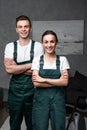 cheerful young professional cleaners standing with crossed arms and smiling