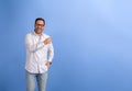 Cheerful young salesman laughing and aiming at copy space for marketing on isolated blue background