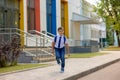 Cheerful young schoolboy in white shirt, blue tie and backpack runs from school Royalty Free Stock Photo