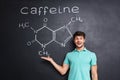 Cheerful young scientist showing chemical structure of caffeine molecule Royalty Free Stock Photo