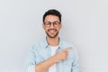 Cheerful young smiling bearded male model wearing trendy glasses, points away, demonstrates something at blank copy space for your Royalty Free Stock Photo