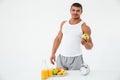 Cheerful young sportsman holding apple. Looking at camera.