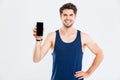 Cheerful young sportsman standing and holding blank screen mobile phone Royalty Free Stock Photo