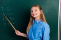 Cheerful young student pointing to math problems on the chalkboard during a classroom lesson in a vibrant learning Royalty Free Stock Photo