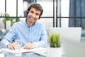 Cheerful young support phone male operator in headset, at workplace while using computer, help service and client Royalty Free Stock Photo