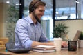 Cheerful young support phone male operator in headset, at workplace while using laptop Royalty Free Stock Photo