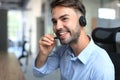 Cheerful young support phone male operator in headset, at workplace while using laptop Royalty Free Stock Photo