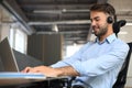 Cheerful young support phone male operator in headset, at workplace while using laptop Royalty Free Stock Photo