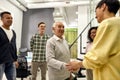 Cheerful young team greeting new employee hired worker in the modern office, Aged man or senior intern shaking hands Royalty Free Stock Photo