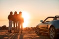 Cheerful young three women standing near cabriolet wathing at sunset Royalty Free Stock Photo