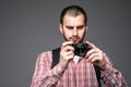 Cheerful young tourist with backpack, old photo camera and smartphone on selfie stick over gray background Royalty Free Stock Photo