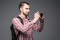 Cheerful young tourist with backpack, old photo camera and smartphone on selfie stick over gray background Royalty Free Stock Photo