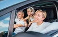 Cheerful young traditional family has a auto journey in modern car. Mother, father and daugher with headphones. Safety riding car Royalty Free Stock Photo