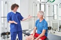 Cheerful young trainer smiling and congratulating his senior patient after successful treatment Royalty Free Stock Photo
