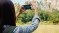 Cheerful young traveler Asian lady with backpack using smartphone for take a picture at mountain lake. Royalty Free Stock Photo