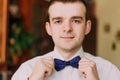 Cheerful young well dressed man fixing his bow tie smiling happily to the camera Royalty Free Stock Photo