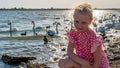 Cheerful young woman in a beautiful dress on the background of birds swans on the lake on a summer day