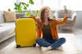 Cheerful young woman with bright suitcase taking selfie, getting ready for vacation at home Royalty Free Stock Photo