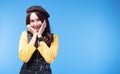 Cheerful woman brunette long hair wear hat holding hand on her face while standing over isolated blue background Royalty Free Stock Photo