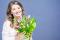 Cheerful young woman with bunny ears and Easter egg basket and tulips Flowers Looking at camera Royalty Free Stock Photo