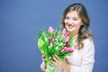 Cheerful young woman with bunny ears and Easter egg basket and tulips Flowers Looking at camera Royalty Free Stock Photo