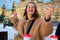 Cheerful young woman with cardboard cup with hot drinks dance and laugh. Christmas Fair in Moscow on Red Square Royalty Free Stock Photo