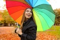 Cheerful young woman with colorful umbrella smiling back. Girl in park with raincoat and umbrella in the autumn Royalty Free Stock Photo