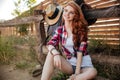 Cheerful young woman cowgirl sitting and smiling outdoors Royalty Free Stock Photo