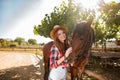 Cheerful young woman cowgirl standing with her horse in village Royalty Free Stock Photo