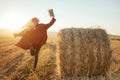 Cheerful young woman, dancing and jumping while reading an exciting book in the field outside